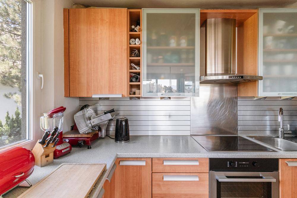Funktionale Küche mit Holzschränken, modernen Geräten und Fenster für Tageslicht.