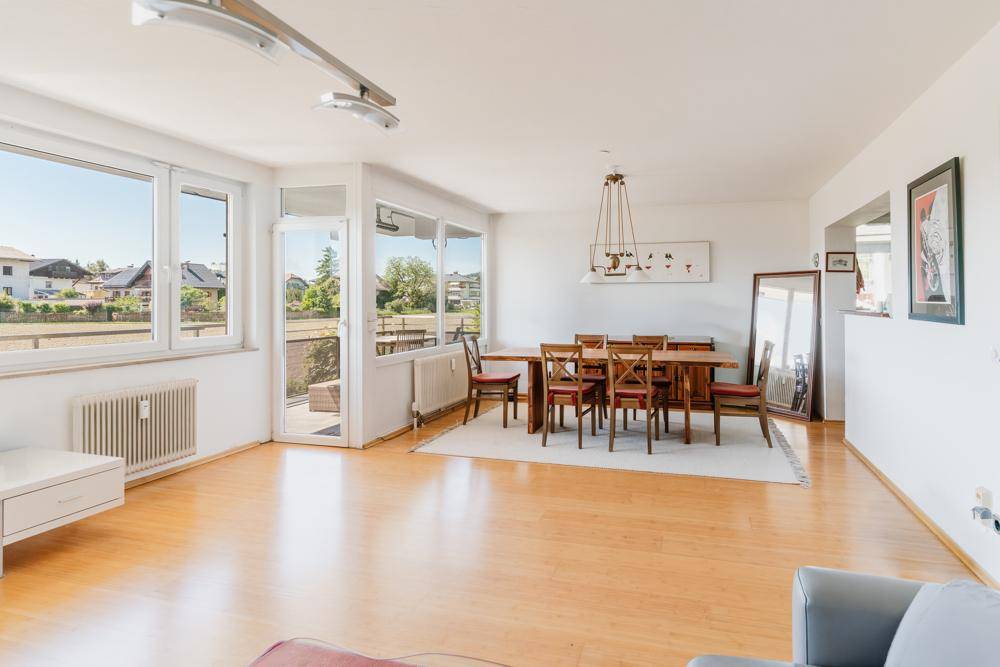 Heller Essbereich mit Holztisch, Stühlen und Zugang zu einem Balkon mit Weitblick.