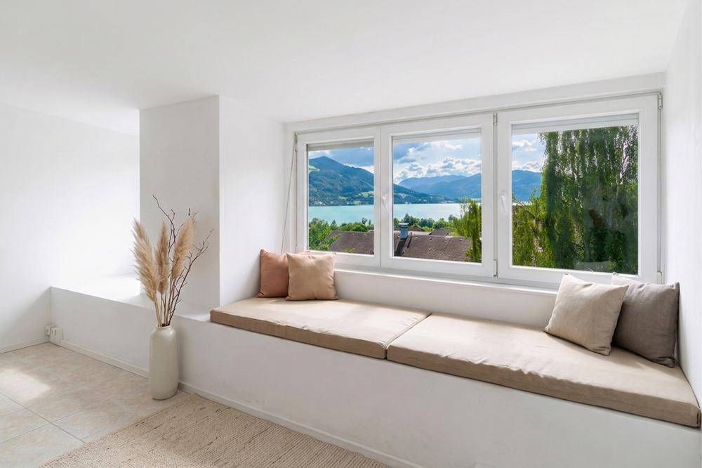 Heller Raum mit gemütlicher Fensterbank und atemberaubendem Blick auf den See und die Berge.