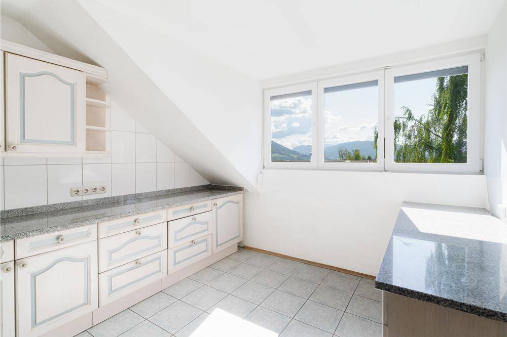 Helle Küche mit weißen Schränken, Granitarbeitsplatten und schöner Aussicht auf die Berge.