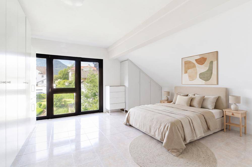 Helles Schlafzimmer mit großem Fenster, Fliesenboden und modernem Bett.