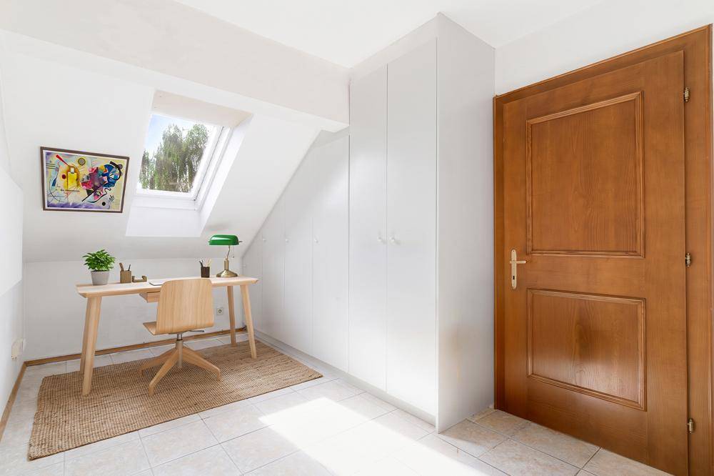 Helles Arbeitszimmer mit Schreibtisch, Stuhl und einem Dachfenster für viel Tageslicht.
