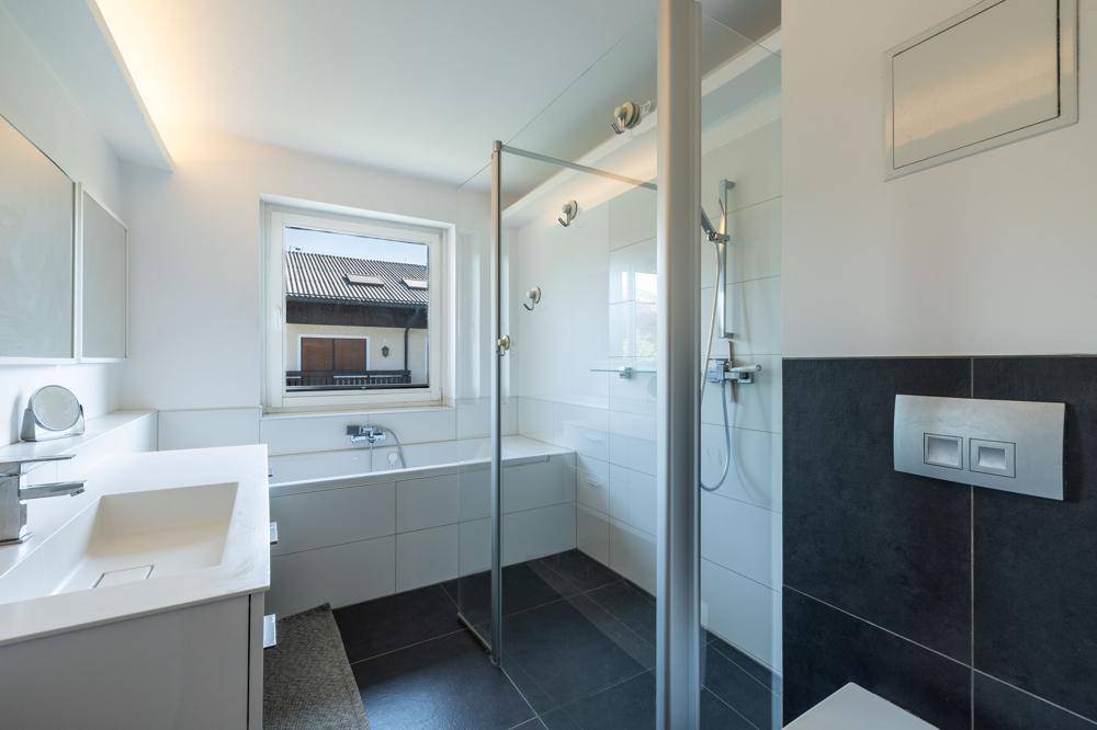 Modernes Badezimmer mit Dusche, Badewanne, Einzelwaschbecken und Fenster für Tageslicht.