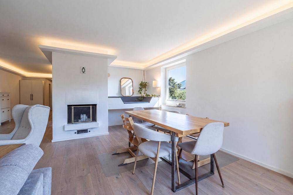 Essbereich mit Holztisch, modernen Stühlen und Kamin, verbunden mit dem Wohnbereich.