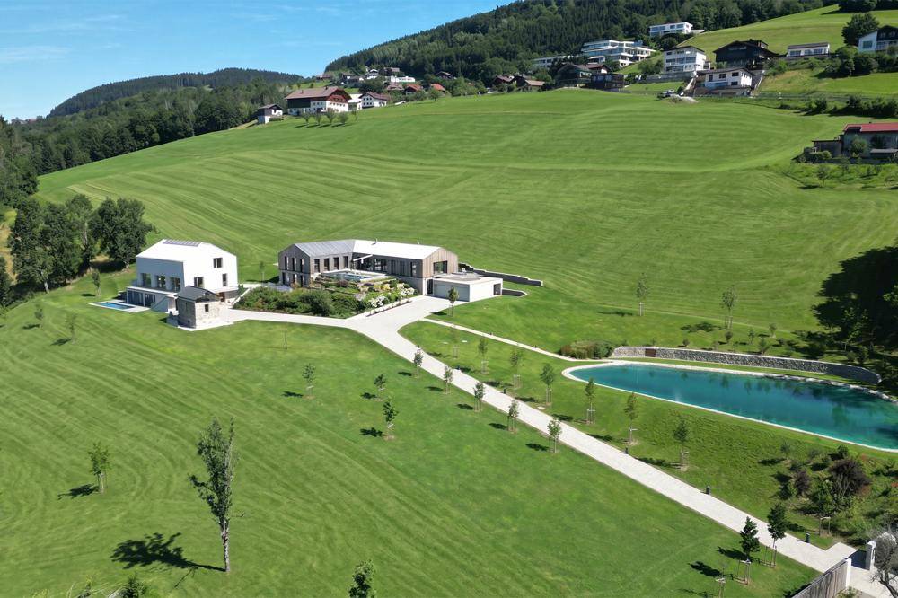 Großzügige Immobilienanlage in hügeliger Landschaft mit modernen Gebäuden, Pool und weitem Blick.