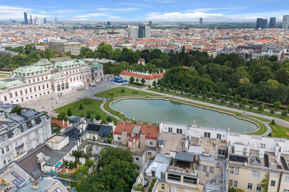 Weitläufiger Luftbildblick auf das Schloss Belvedere, die Parkanlage und die Dächer der Stadt Wien.
