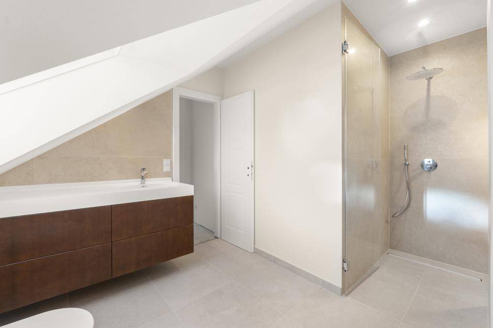 Modernes Badezimmer mit begehbarer Dusche, Einzelwaschbecken und schräger Dachschräge.