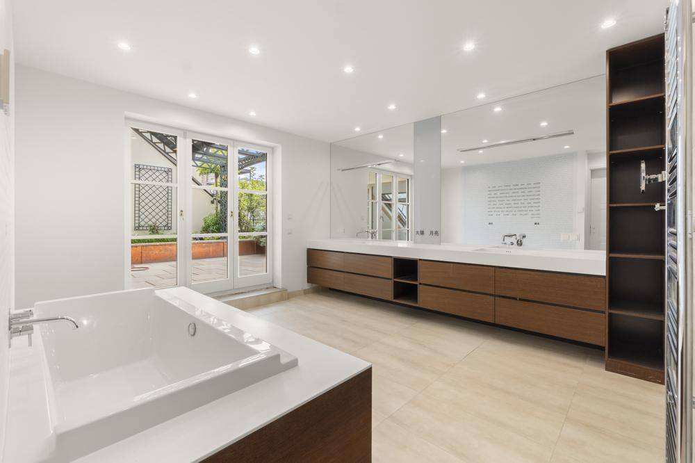 Modernes Badezimmer mit Badewanne, Doppelwaschbecken und direktem Zugang zu einer Außenterrasse.