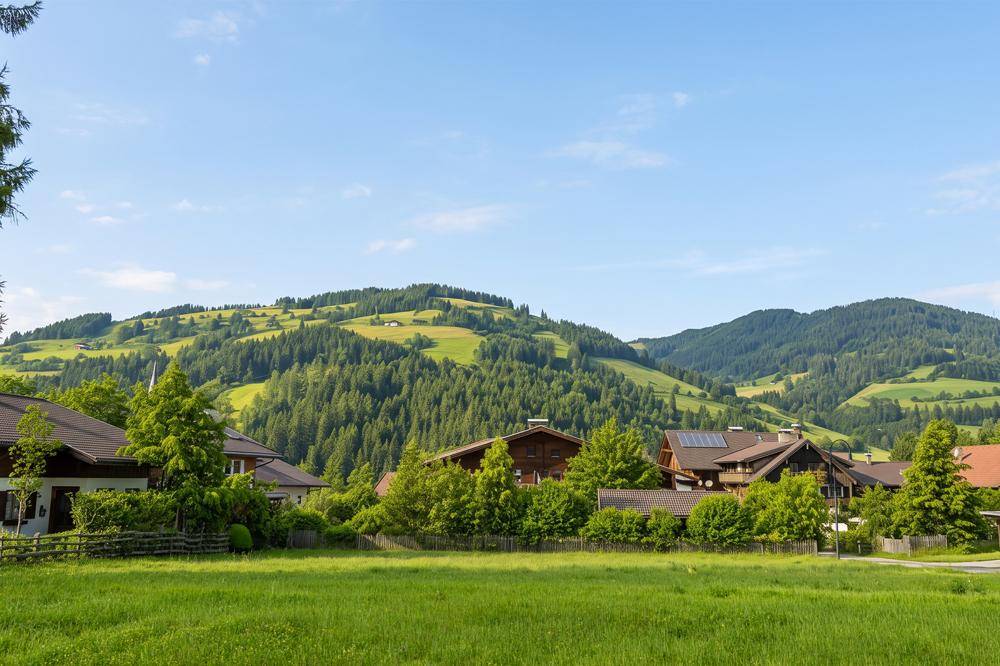 Häuser mit Solaranlagen auf den Dächern, eingebettet in eine grüne Hügellandschaft.