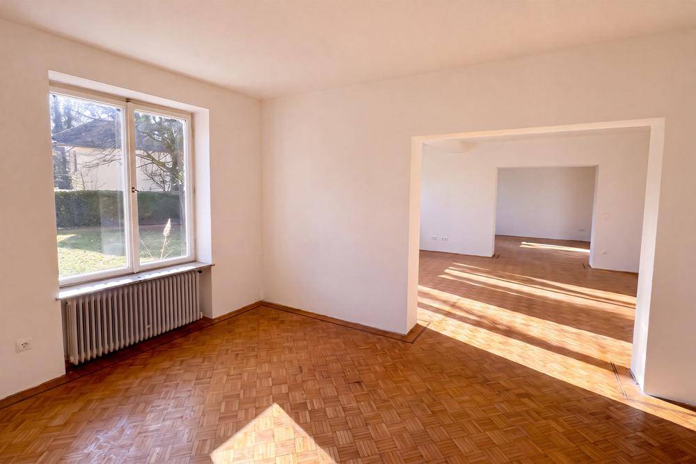 Heller, leerer Essbereich mit Parkettboden und Blick ins Grüne.