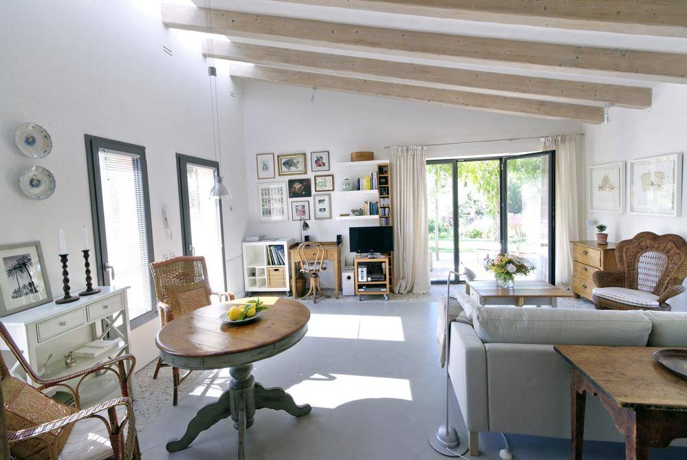 Helles Wohnzimmer mit hohen Decken, Holzbalken und Zugang zum Garten.