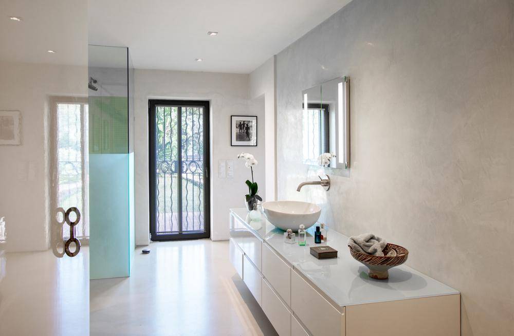 Modernes Badezimmer mit freistehendem Waschbecken, großer Dusche und Zugang nach draußen.