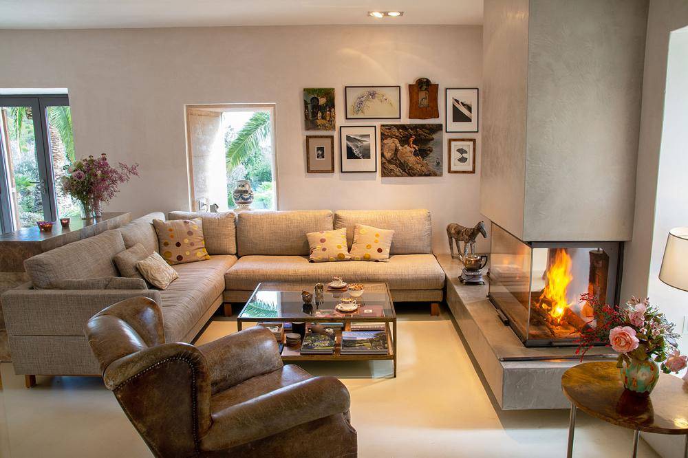 Helles Wohnzimmer mit modernem Kamin, bequemen Sofas und Kunstwerken an der Wand.