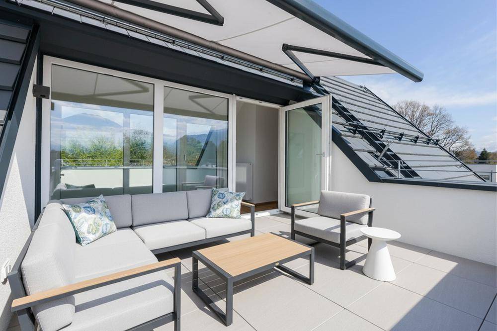 Geräumige Dachterrasse mit modernen Loungemöbeln und weitem Blick auf die Berglandschaft.