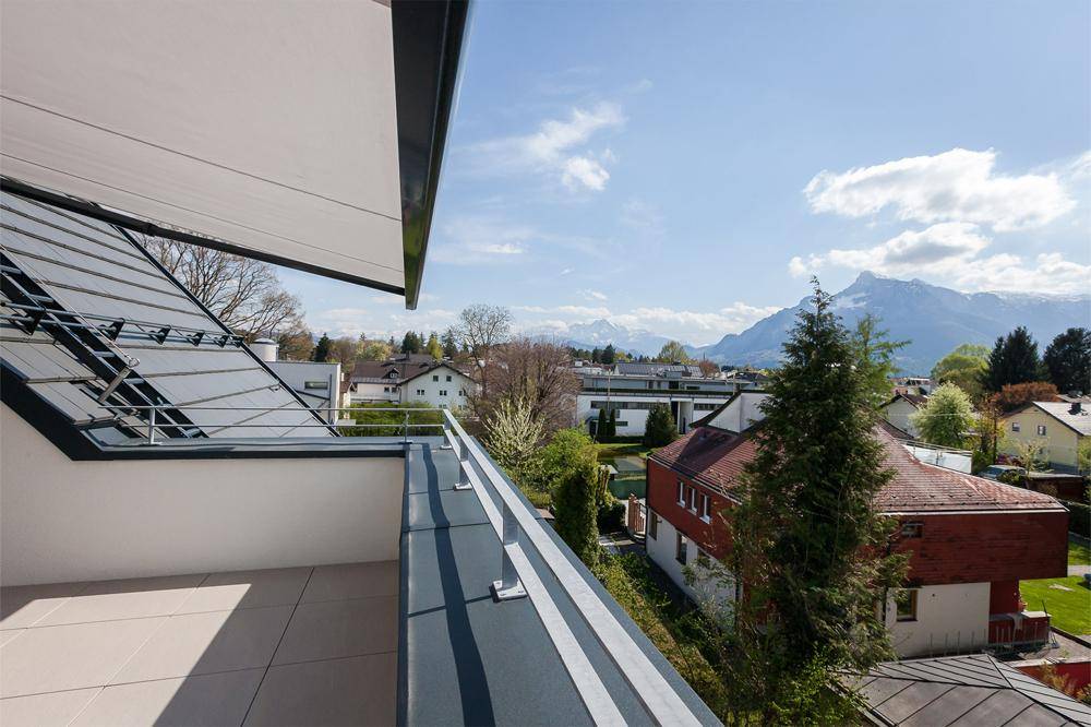 Balkon mit Markise und weitem Blick auf die umliegende Berglandschaft und Häuser.