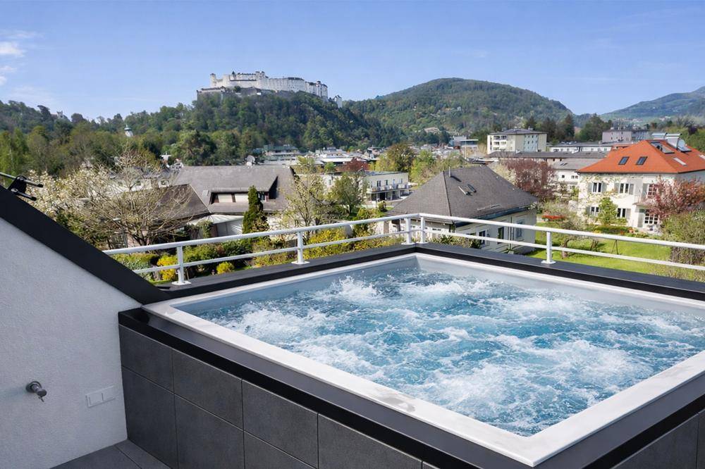 Dachterrasse mit Whirlpool und Panoramablick auf die Stadt und die umliegenden Berge.