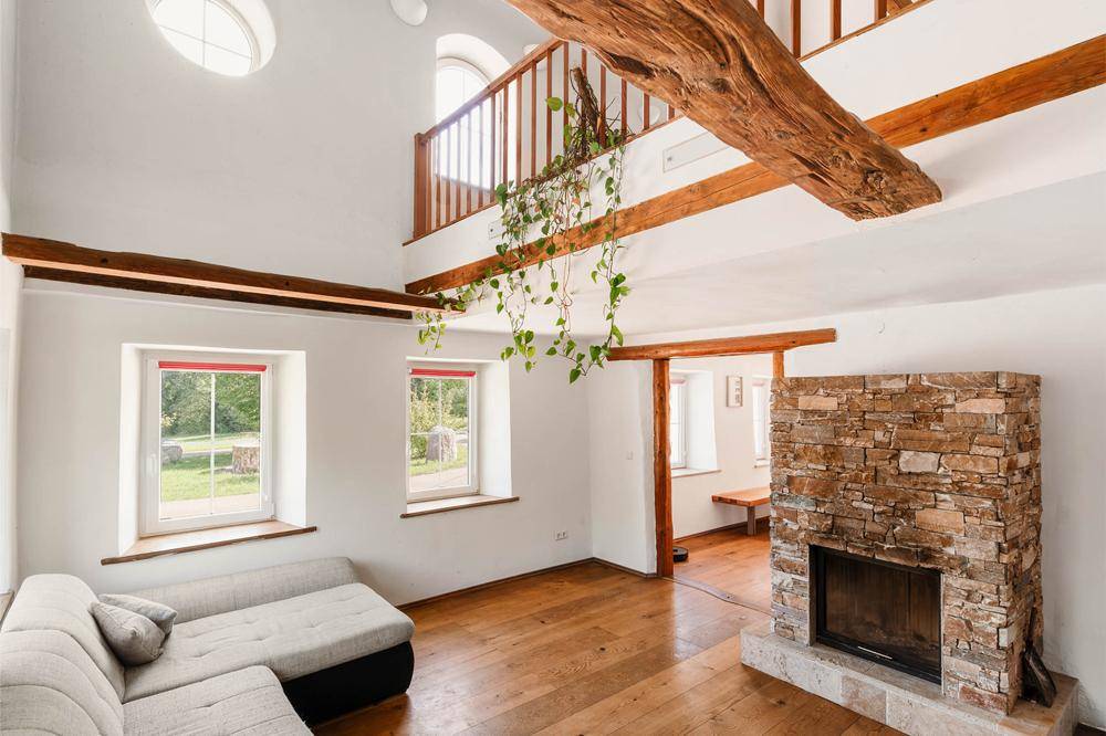 Helles Wohnzimmer mit Holzboden, Kamin und sichtbaren Holzbalken, offen zur Galerie.