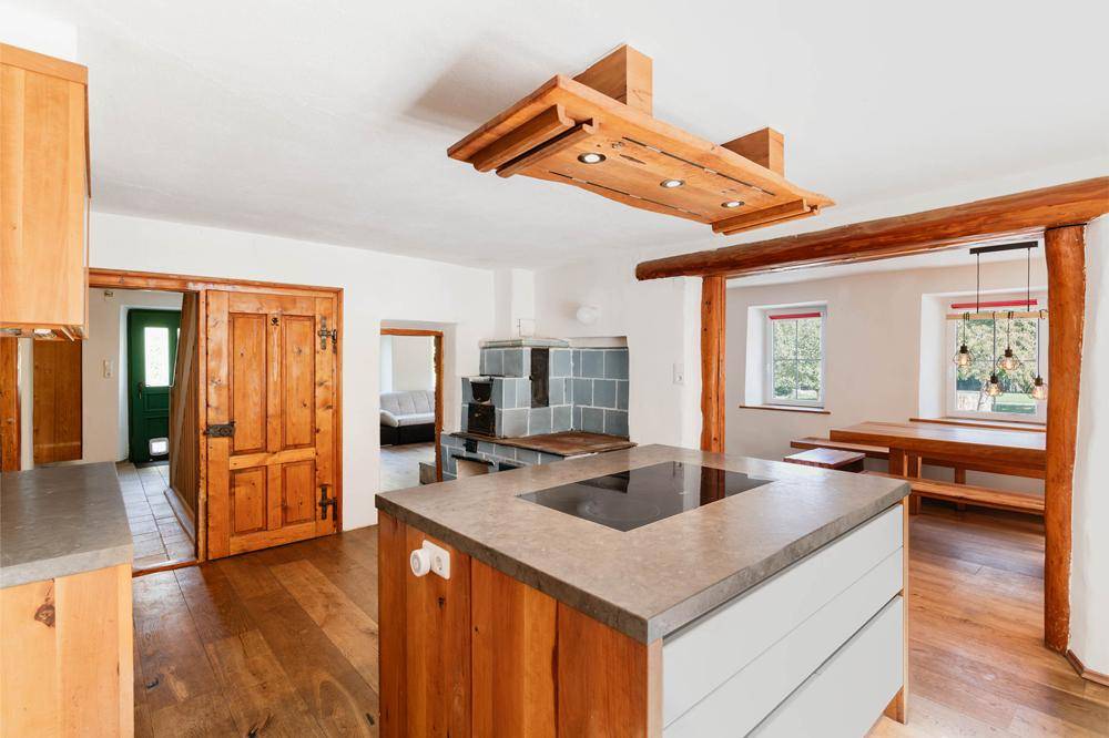 Geräumige Küche mit Kochinsel, Induktionskochfeld und Holzelementen, verbunden mit Essbereich.