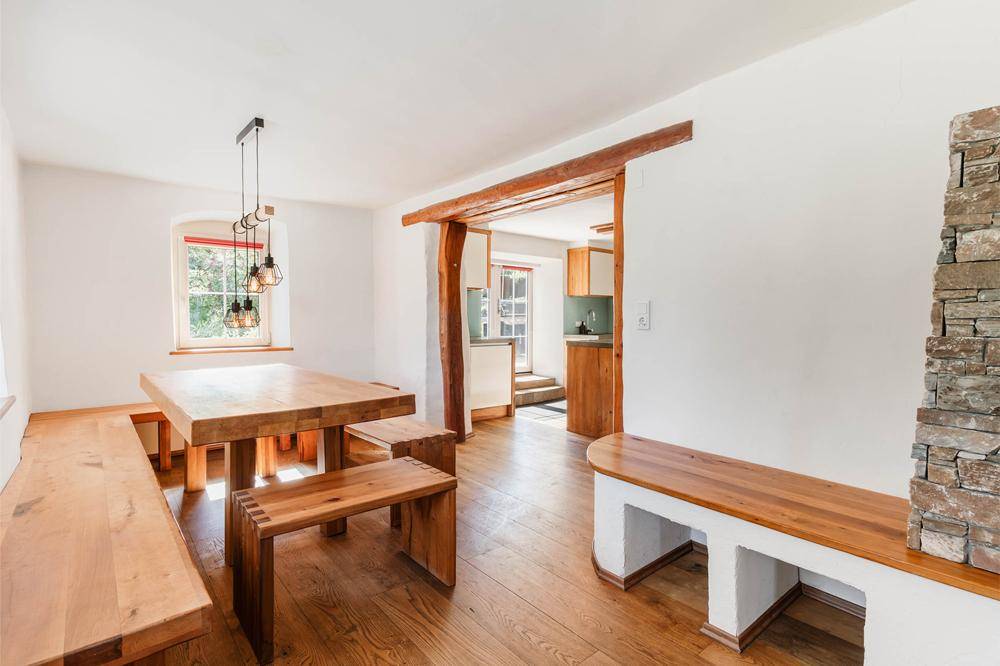 Rustikaler Essbereich mit massivem Holztisch und Bänken, verbunden mit der Küche.