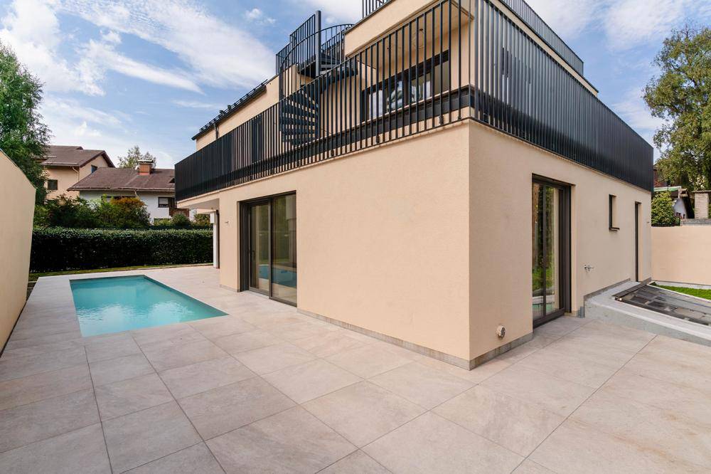 Außenansicht des modernen Gebäudes mit Poolbereich und gepflegtem Garten mit Hecke.