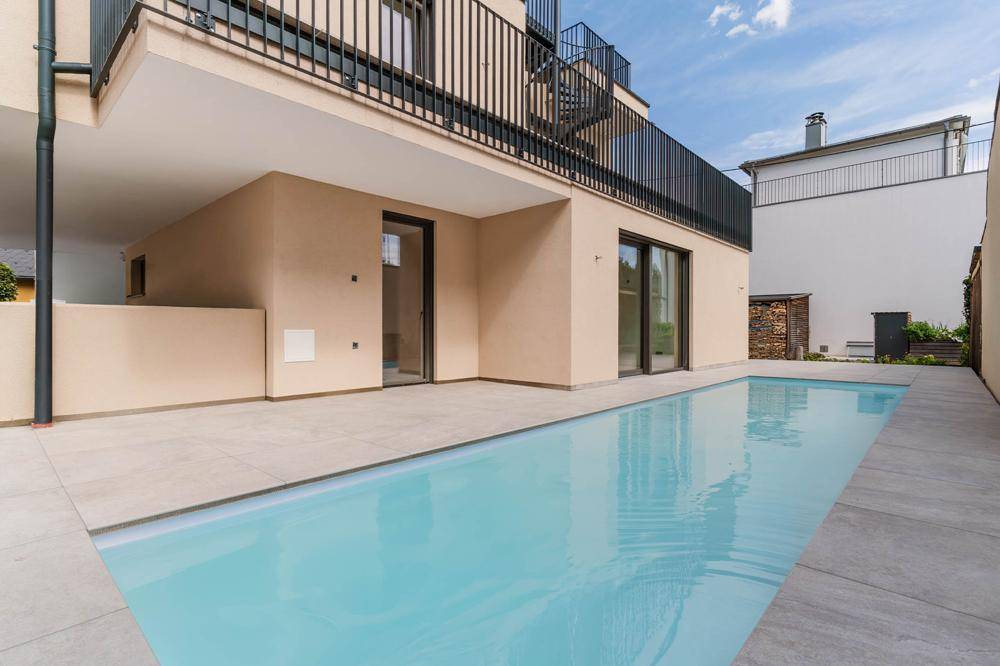 Moderner Außenbereich mit Swimmingpool und großzügiger Fliesenterrasse am Gebäude.