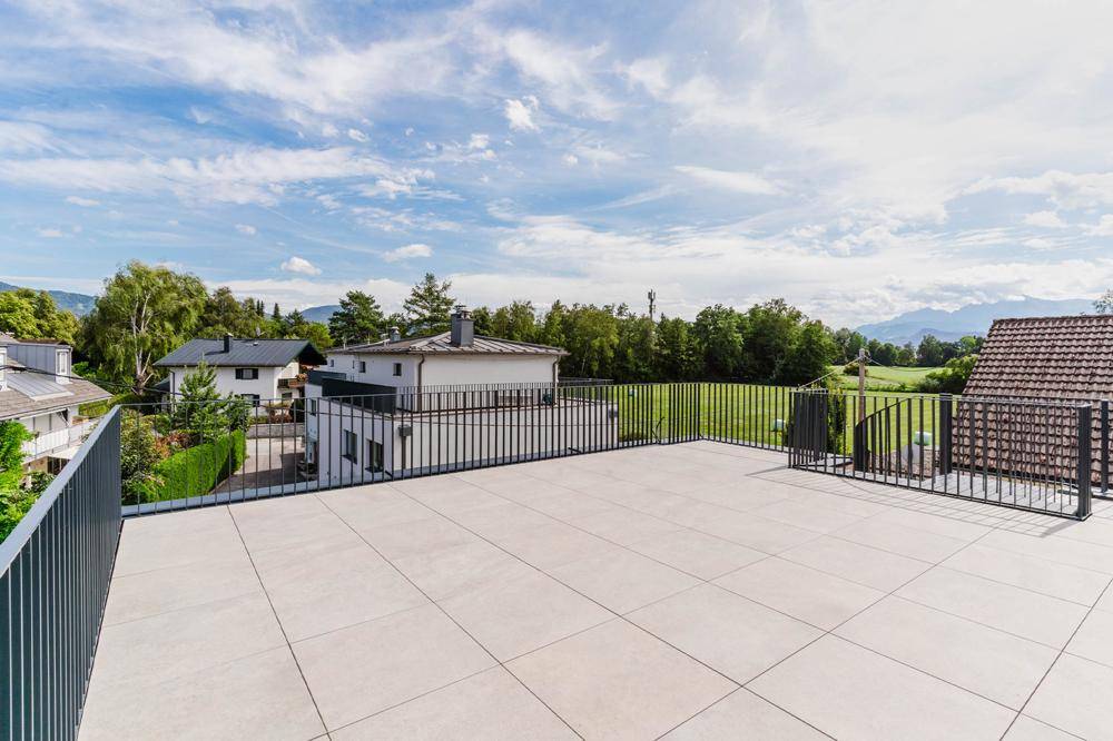 Große Dachterrasse mit weitem Blick über grüne Felder und die umliegende Landschaft.