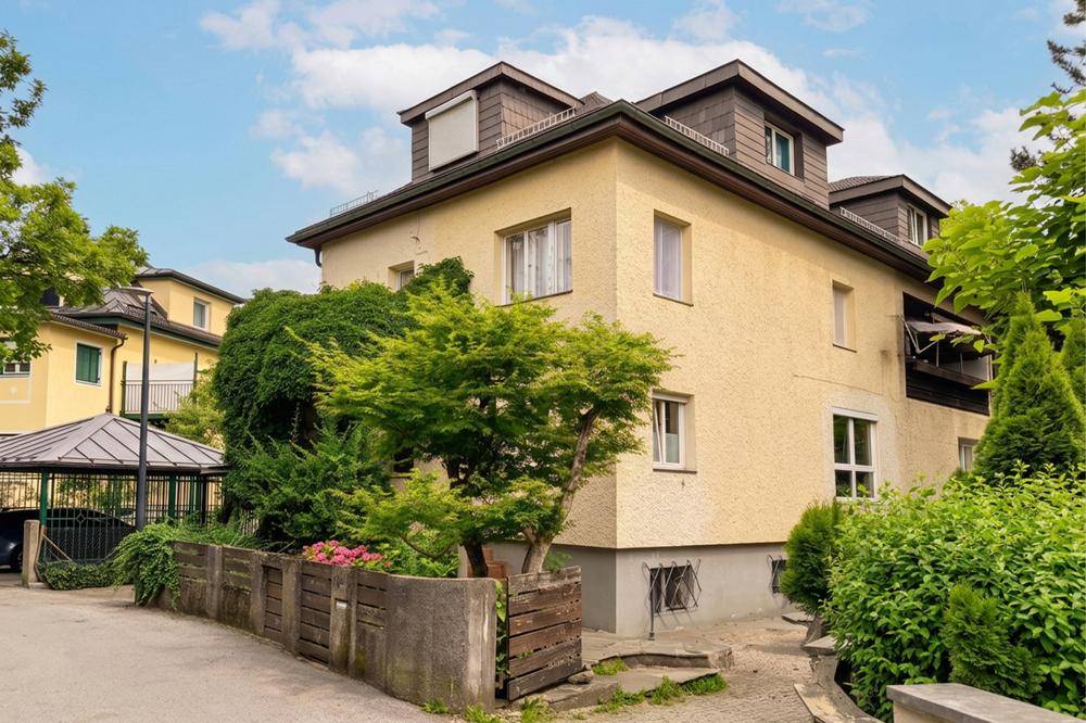 Seitenansicht des Hauses mit gepflegter Bepflanzung und Zufahrt zum Carport.