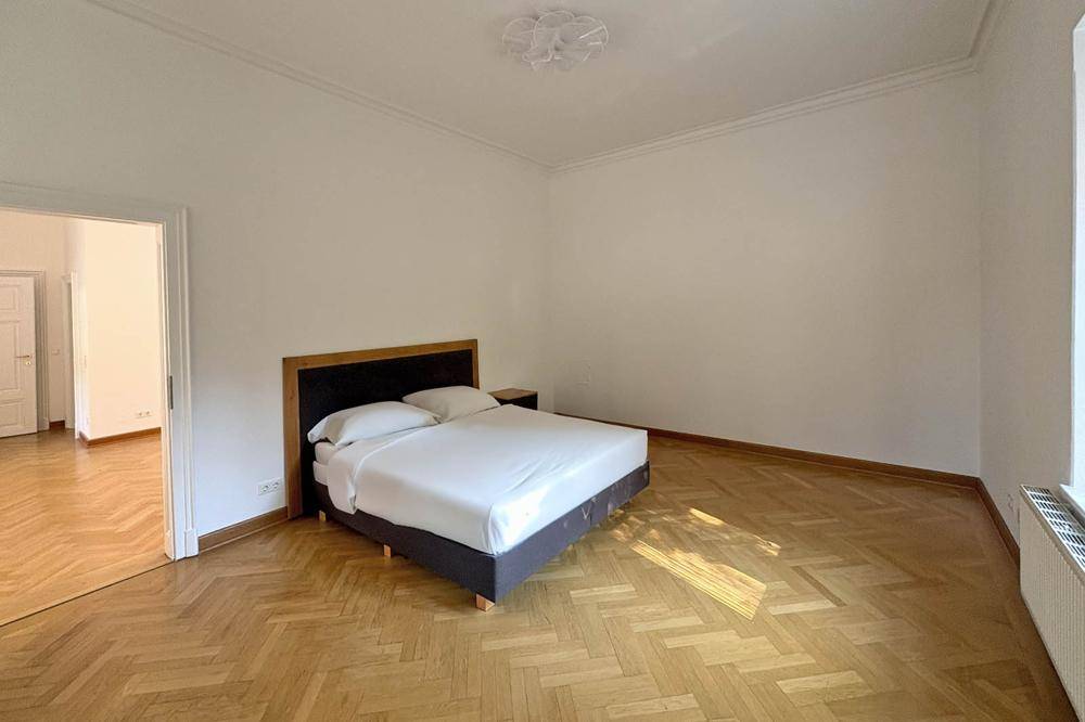 Geräumiges Schlafzimmer mit Fischgrätparkett und viel Tageslicht, bereit zur individuellen Einrichtung.