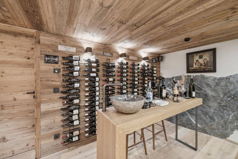 Stilvoller Weinkeller mit umfangreichen Weinregalen, Holztresen und Natursteinwand.