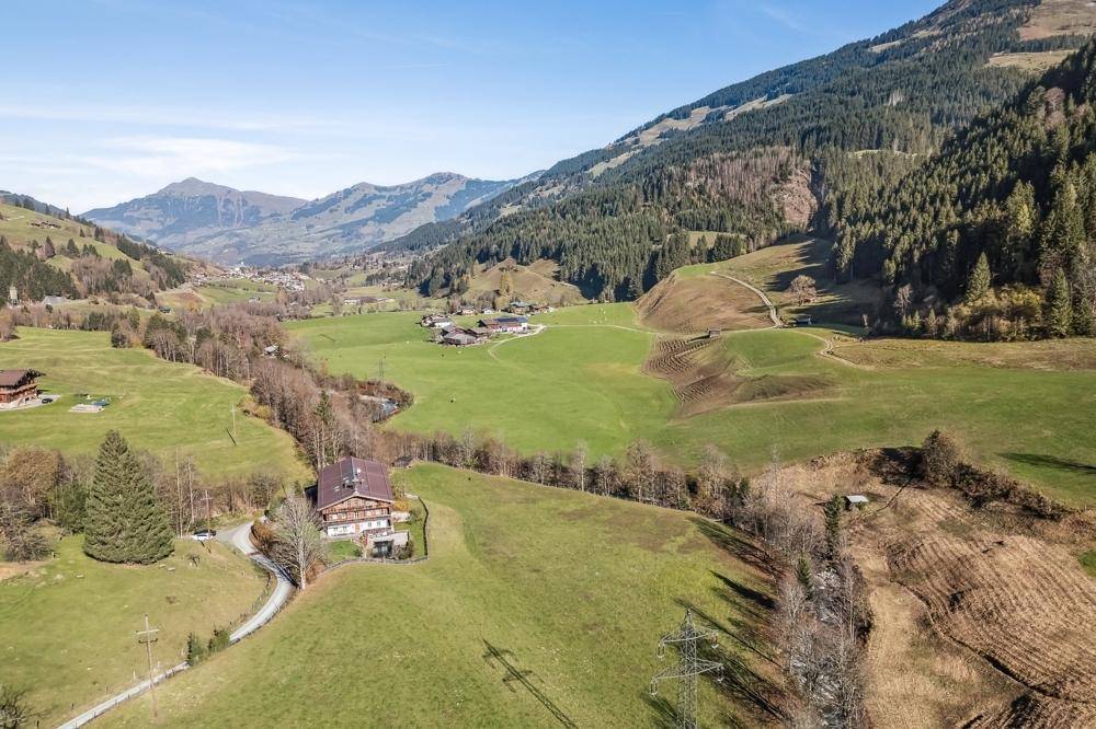 Luftaufnahme des Anwesens in einem weiten Tal, umgeben von grünen Wiesen und bewaldeten Bergen.