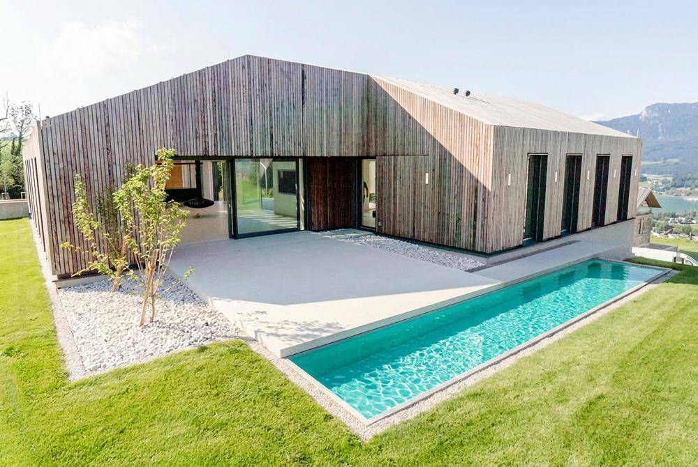 Modernes Haus mit Holzfassade, großem Infinity-Pool und weitem Blick auf die umliegende Landschaft.