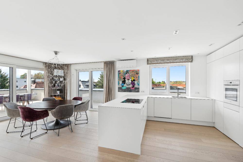 Moderne, offene Küche mit Essbereich, weißer Kücheninsel und direktem Zugang zur sonnigen Terrasse.