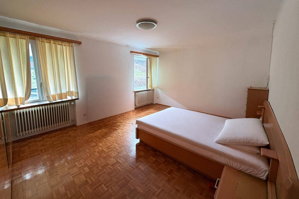 Geräumiges Schlafzimmer mit Parkettboden, zwei Fenstern und einem Doppelbett, hell und funktional.