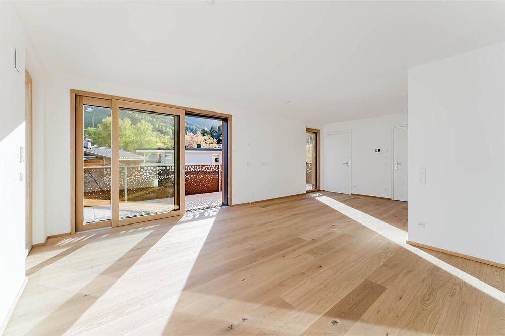Geräumiges, helles Wohnzimmer mit Eichenparkett und Schiebetüren zum Balkon, ideal für offenes Wohnen.