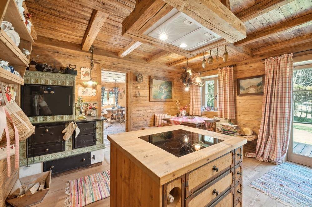 Rustikale Holzküche mit traditionellem Kachelofen und moderner Kochinsel mit Induktionskochfeld.