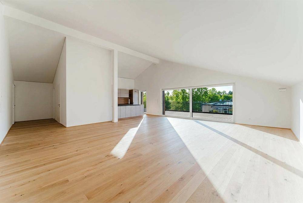 Heller, offener Wohnbereich mit Holzboden, Dachschrägen und Zugang zur Terrasse.