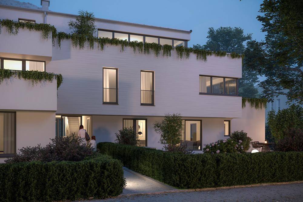 Moderne Gebäudefassade bei Dämmerung mit begrünten Terrassen und gepflegter Außenanlage.