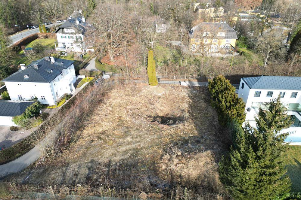 Luftaufnahme eines unbebauten Grundstücks mit umliegenden Häusern und viel Grün.