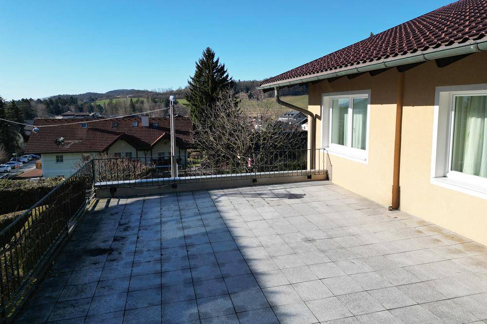 Große geflieste Terrasse mit Metallgeländer und weitem Blick über die Nachbarschaft und Landschaft.