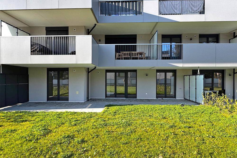 Moderne Wohnanlage mit Balkonen, Terrassen und direktem Zugang zu privaten Gartenbereichen.