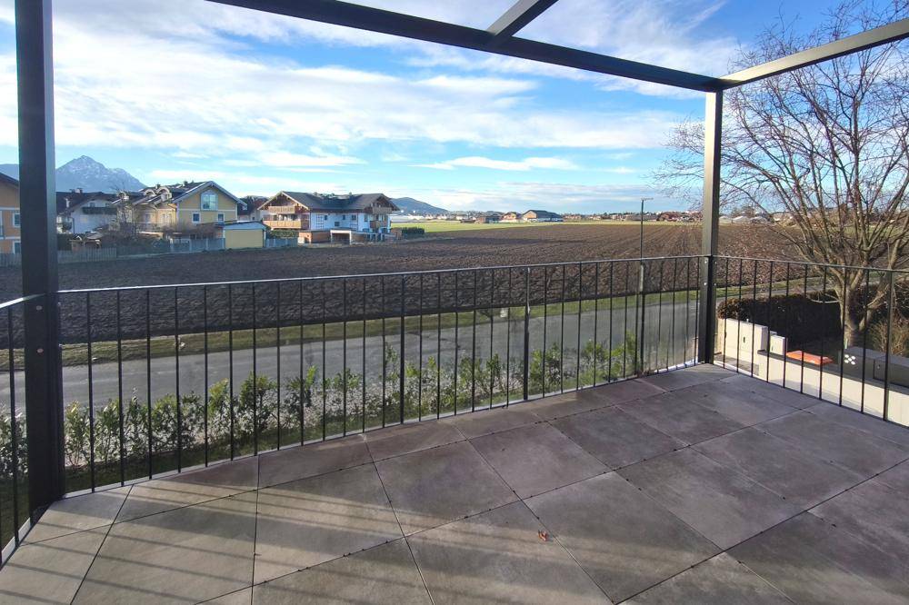 Große geflieste Terrasse mit weitem Blick über die Landschaft und Berge im Hintergrund.
