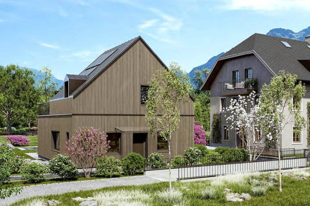 Zwei moderne Häuser mit Holzfassaden und gepflegten Gärten in bergiger Landschaft.
