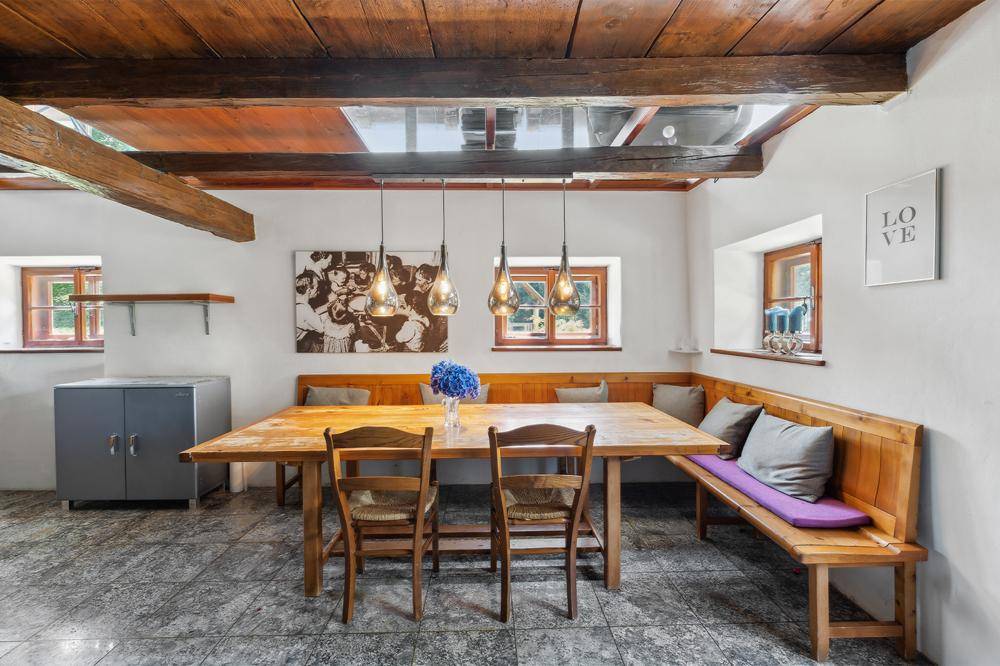 Gemütlicher Essbereich mit rustikalen Holzbänken, großem Tisch und sichtbaren Deckenbalken.