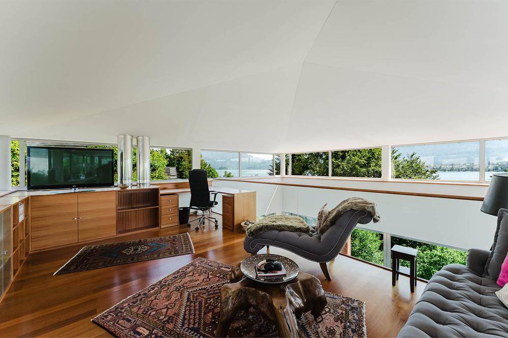 Arbeitsbereich mit Seeblick und großen Panoramafenstern, ideal für produktives Arbeiten.