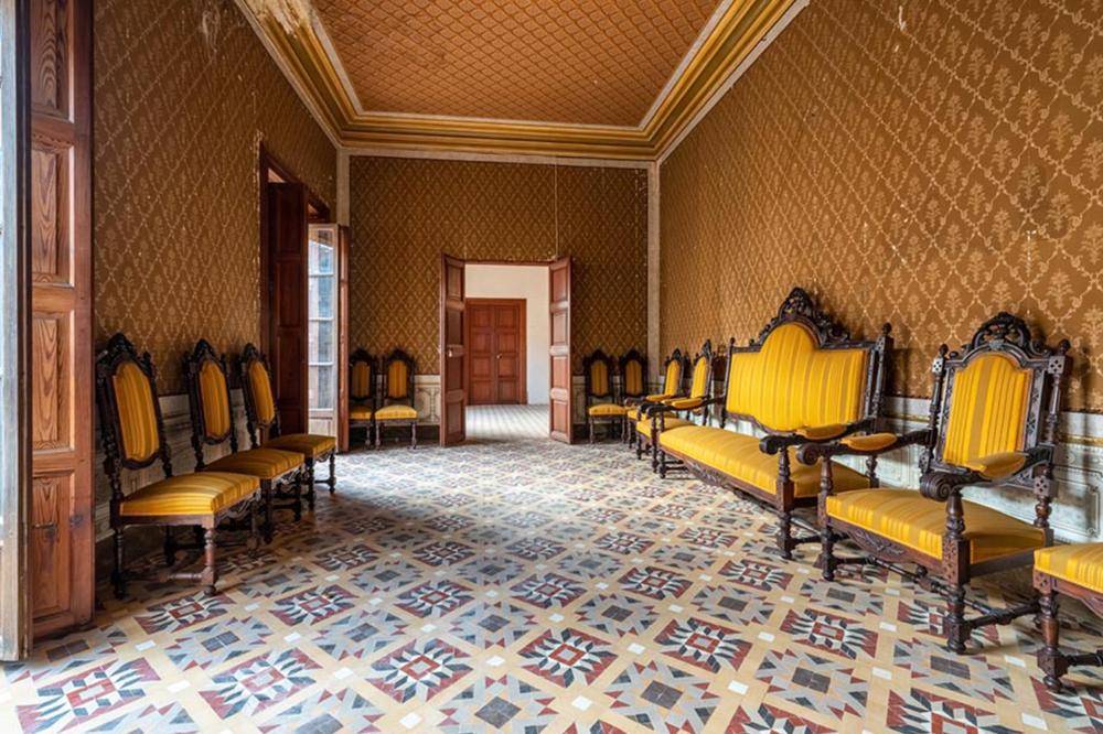 Prunkvoller Salon mit gemusterten Tapeten, historischen Möbeln und farbenfrohem Fliesenboden.
