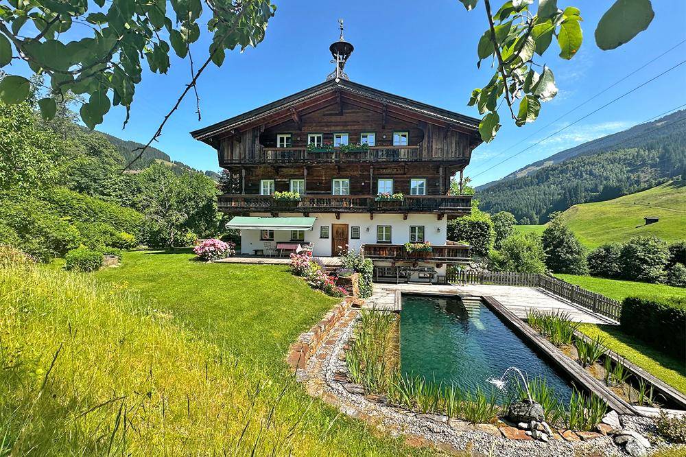 Idyllisches Holzhaus mit großem Garten, Naturpool und weitem Blick auf die grüne Berglandschaft.