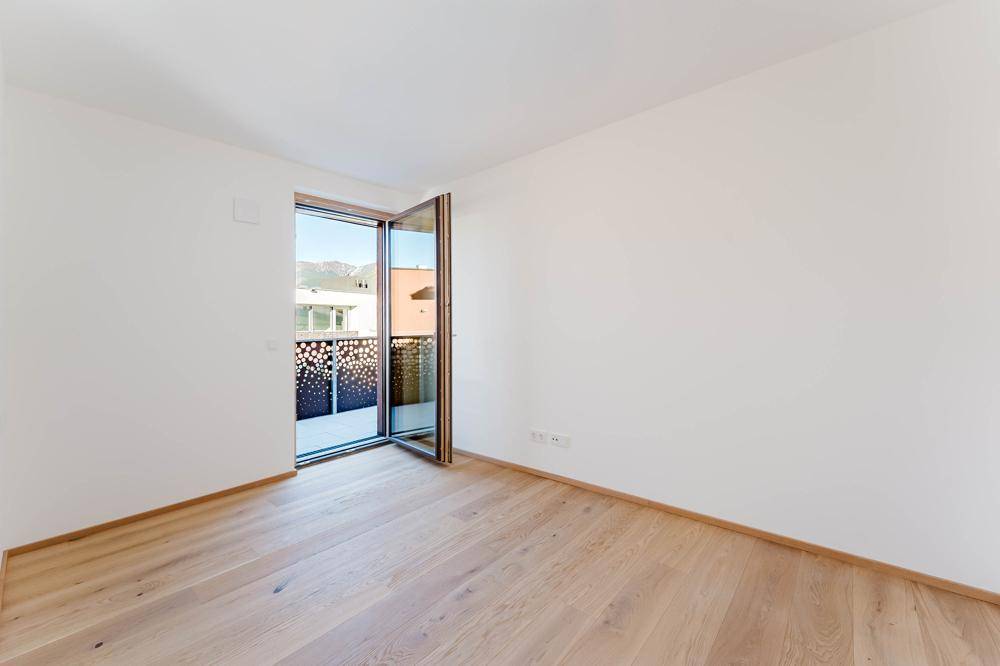 Helles Schlafzimmer mit Holzboden und Zugang zu einem Balkon, bietet eine angenehme Wohnatmosphäre.