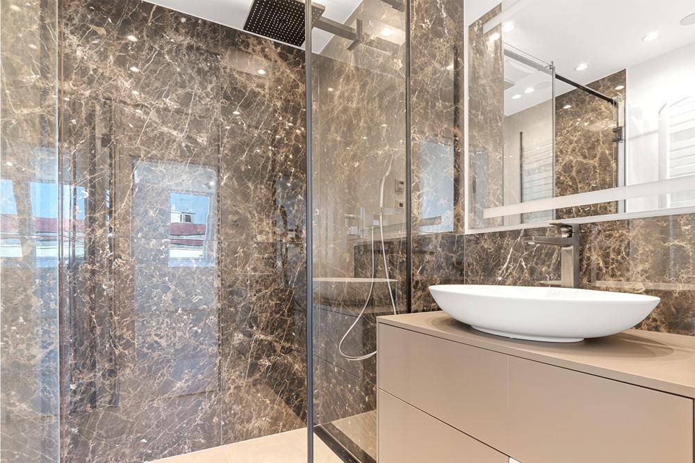 Modernes Badezimmer mit dunklen Marmorfliesen, begehbarer Dusche und elegantem Waschbecken.