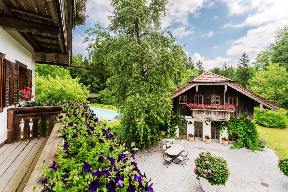 Balkon mit Blumenkästen und Blick auf den Garten, den Pool und das Nebengebäude des Anwesens.