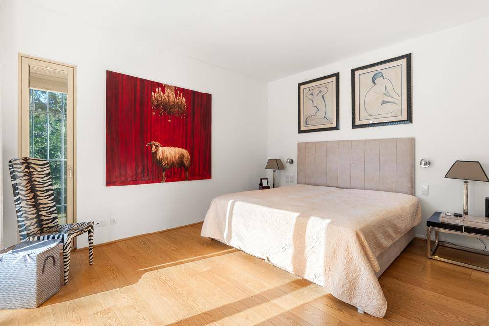 Schlafzimmer mit Doppelbett, Holzboden und farbenfroher Kunst an der Wand, hell und geräumig.